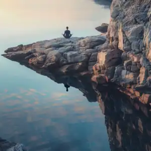 person doing mantra jaap on rock by calm water with clear reflection at sunrise