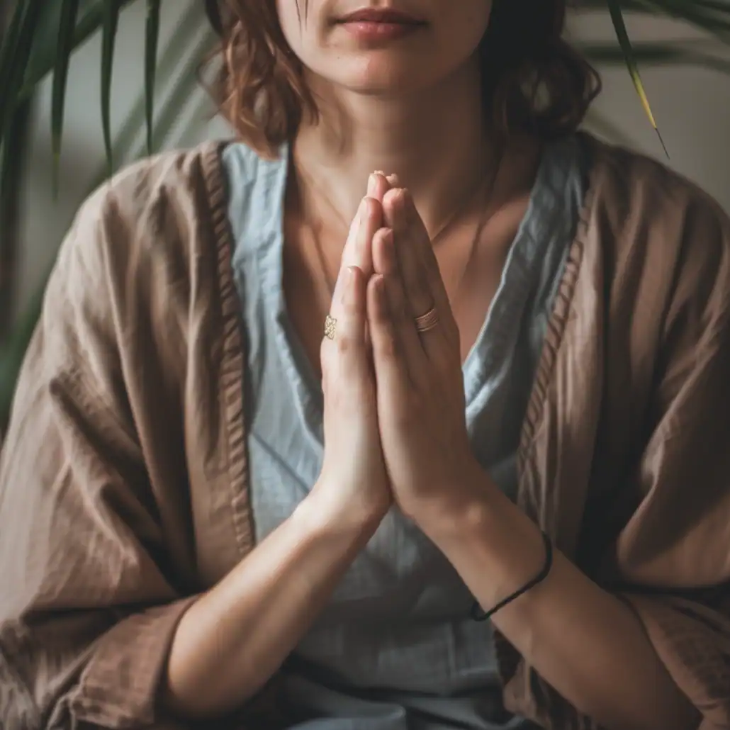 Person with hands folded in prayer position at heart center, representing focus, devotion, and inner calm